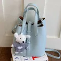 Light blue leather bucket bag with top handles, adjustable shoulder strap and cute bear charm. - Blue With Pendant