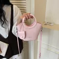Stylish pink woven bucket handbag with circular handle and adjustable crossbody strap - Pink