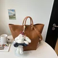 Vue détaillée du sac cabas en cuir tressé marron, texture fine et charmant pendentif lapin. - Brun Avec Pendentif