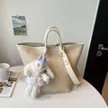 Vue détaillée de l'élégant sac cabas tressé en cuir beige avec bandoulière et charm en peluche. - Beige Avec Charme