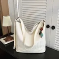 Detailed view of the white woven leather bucket bag with chic texture and charm accent. - With Pendant / Off White