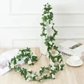 Detailed view of artificial white rose vine with green leaves in home decor setting. - Spring Peony Vine White