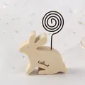 Minimalistischer hölzerner Hasen-Notizhalter mit Metallspirale auf weißem Sternenhintergrund - Kaninchen