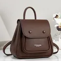 Detailed view of a brown pebbled leather backpack with elegant front pocket design. - Coffee