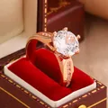 Detailed close-up view of a rose gold six-prong moissanite ring in a red velvet gift box. - Size 6 / Rose Gold