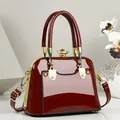 Détail d'un sac à main élégant en cuir verni rouge foncé avec ferrures dorées de luxe - 21*11*15 / Bordeaux
