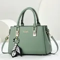 Elegante saliegroene dameshandtas van kunstleer met een zijden sjaalbedeltje en metalen KUOY-logo - 28x12x20cm / Groen