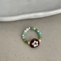 Detailed close-up of a handmade beaded elastic ring with green stones and a pearl - Green Stone Flower Style
