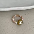 Close-up view of an elastic ring featuring natural stones, pearls, and flower bead - Coffee Stone Flower Style