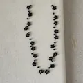 Detailweergave van handgemaakte zwarte kralenketting met bloemen op een canvas achtergrond - Zwart