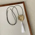 Close-up of minimalist gold shell pendant with white tassel on black cord necklace - Gold Adjustable Necklace