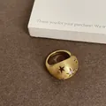 Primo piano di un anello dorato con texture spazzolata e motivi a stella traforati - Stile Ovale Spazzolato Stella Traforata / Oro