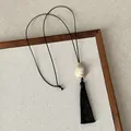 Detailed view of a Zen style black tassel necklace featuring a cream-colored stone pendant. - Beige Grey Resin Necklace