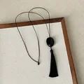 Detailed view of a black Zen-style tassel necklace on a textured linen display tray - Black Resin Necklace