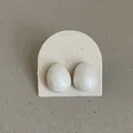 Close-up of white oval stud earrings with a pearlescent finish on a display card - Marble Pattern Oval Bean Style / White