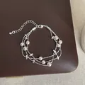 Close-up detail of an elegant multi-strand pearl bracelet with silver-tone beads - Three-Layer Beaded Style (Style 5)