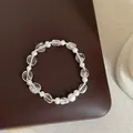 Detailed view of an irregular clear crystal and pearl bracelet on a brown surface - Model 1 Bracelet (Pearl and White Crystal)