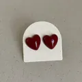 Detail view of glossy dark red heart shaped stud earrings with a smooth enamel finish - Bold Heart Style / Dark Red