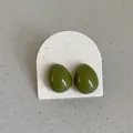 Detailed view of glossy olive green bean-shaped enamel stud earrings on a display card - Geometric Oval Style / Olive Green