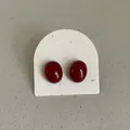 Close-up detail view of deep red oval stud earrings with smooth glossy enamel finish - Oval Bean Style (Style 13) / Dark Red
