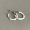 Close-up view of elegant white enamel hoop earrings with silver-tone metal closure. - Geometric Rings Style / Cream