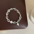 Macro view of clear white crystal bracelet with silver pinecone charm on brown leather. - Model 4 Bracelet (Pinecone and Bead)
