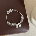 Vue détaillée d'un bracelet en cristal blanc irrégulier avec des breloques argentées - Bracelet Modèle 15 (Cristal Irrégulier et Clochette)