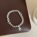 Détail d'un bracelet de perles en cristal clair avec une breloque argentée de bénédiction Nafu - Bracelet Modèle 14 (Étiquette Métallique Nafu)