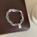 Gros plan d'un bracelet en perles de cristal avec breloque en argent sur fond cuir - Bracelet Modèle 10 (Étiquette Rectangulaire)