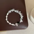 Vue détaillée d'un bracelet en cristal clair et perles sur une surface brune. - Bracelet Modèle 5 (Perle et Double Cercle Métal)