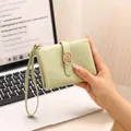 Detailed view of matcha green burst texture short wallet with wrist strap held by hand. - Green