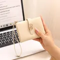 Close-up of a cream-colored crackle-textured short wallet held by a hand. - Apricot