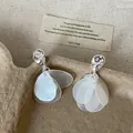 Primer plano de pendientes de plata con detalles de pétalos de concha blanca translúcida - Pendientes de borla de gota de agua / Plateado