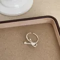 Detailansicht eines silbernen geometrischen Knotenrings in einer Schale - Schleifenknoten Twist Stil (Ring Stil 1)