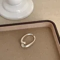 Nahaufnahme eines minimalistischen silbernen geometrischen Rings auf einem beigen Tablett - Stromlinienförmiger Offener Stil (Ring Stil 5)