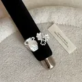 Dettaglio di un anello testurizzato color argento con ciondoli a vaso e fiori su supporto. - Stile Aperto Giarra Floreale Testurizzata / Argento