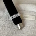 Detailed view of a French style silver lace hollow metal ring on a black display rod - Engraved Pattern Lace Style (Style 30 Ring) / Silver