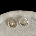 Detail macro view of transparent resin stud earrings with real dried flower and gold leaf. - Round Yellow Flower Earrings