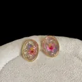 Detail shot of vintage resin earrings featuring preserved real flowers in gold oval frames - Oval Pink Flower Earrings