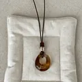 Close-up of vintage amber geometric resin pendant on a long brown cord necklace - Style 1 Amber Ring Necklace