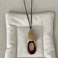 Macro detail of a vintage amber geometric resin pendant on a long dark necklace cord - Style 2 Cream Cone Patchwork Necklace