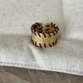 Nahaufnahme eines goldfarbenen strukturierten Rings mit brauner Fadenwicklung Details. - Rotbraune Linie Breiter Ring