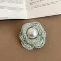 Macro shot of an elegant green tweed camellia flower brooch with a large central pearl - Style 3