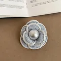 Elegant tweed camellia brooch with a central pearl, featuring a chic braided edge. - Style 7