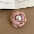Macro close-up view of pink fabric camellia flower brooch with gold chain and pearl center - Style 8