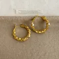 Gedetailleerde close-up van gouden oorringen met een uniek gestructureerd ontwerp - Goud