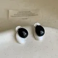 Primer plano de pendientes de botón ovalados minimalistas en esmalte blanco y negro. - Contraste de colores negro, blanco y plata / Plateado