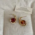 Detail view of vintage amber resin earrings with gold metal frame and small crystal accents - Oval Geometric Style / Coffee