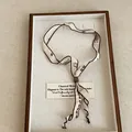 Detail view of a minimalist printed ribbon scarf necklace showcased in a wooden jewelry tray - Beige