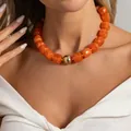 Dettaglio di una collana bohémien con grosse perle di resina arancione su modella - Collana Arancione